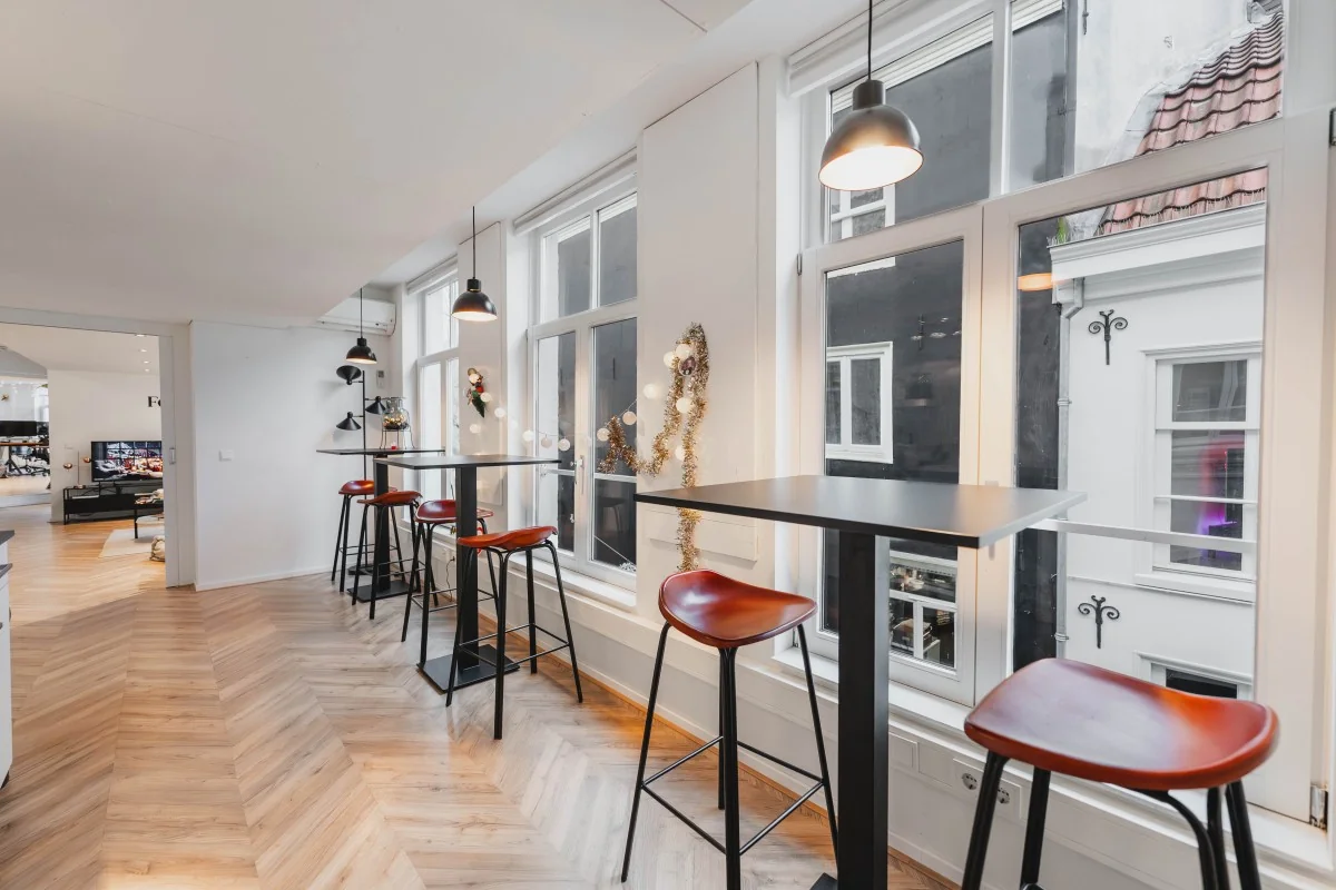 Modern ingerichte zithoek met hoge tafels en barkrukken in een licht appartement aan de Korte Reguliersdwarsstraat.